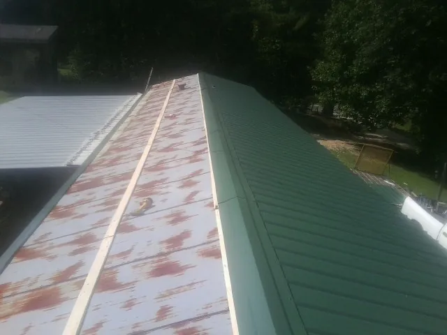 Old rusted panels beside newly installed green metal roofing — Wind Damage Roof Repair by Roofing Brothers in Gate City