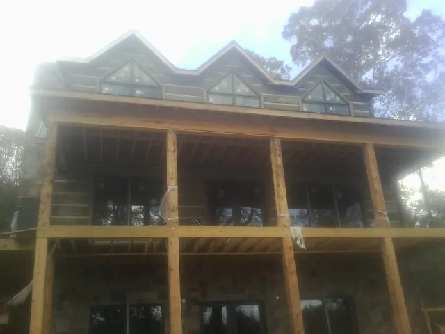 Dormers and porch framing on a large log home under construction — Roof Coating work by our crew in Gate City