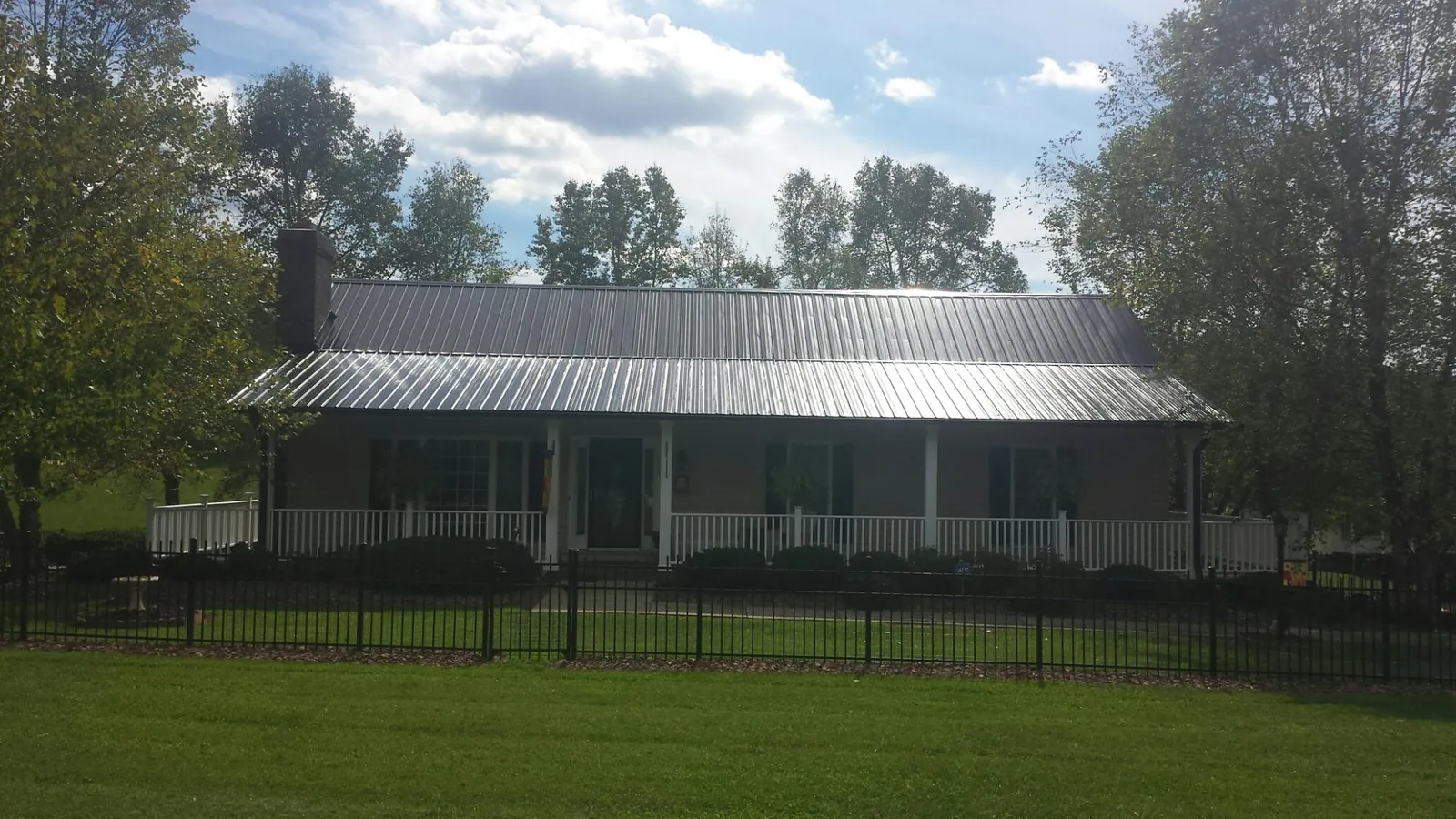 Gray metal roof on a brick ranch with a full width front porch — Gutter Guard Installation work by our crew in Gate City