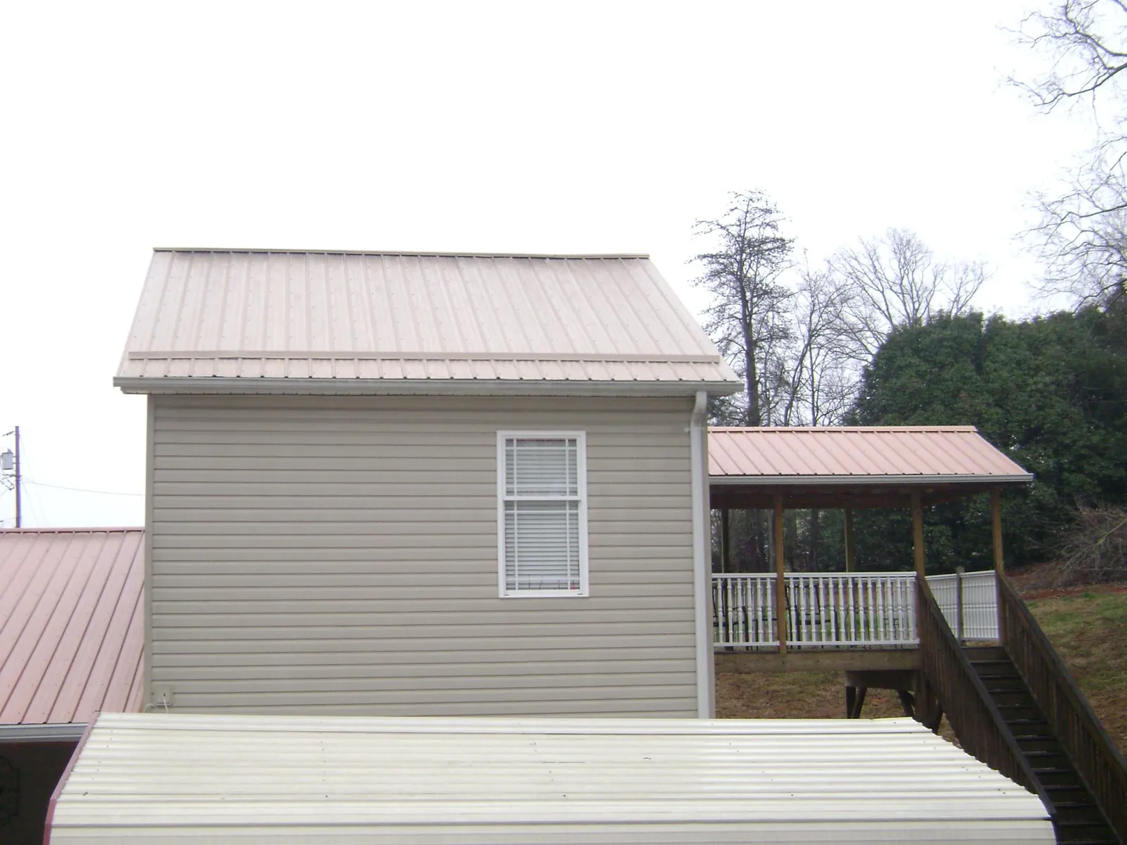 Tan metal roofs on a two story addition and attached porch, from a Roof Replacement job in Gate City