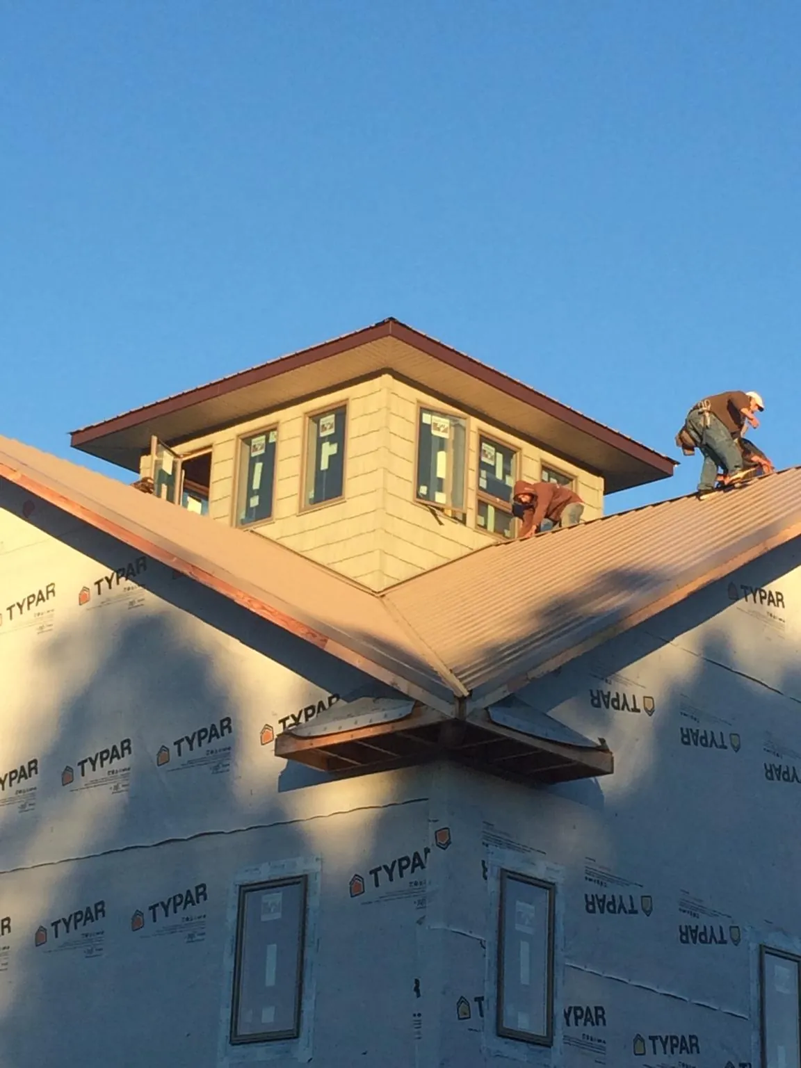 Roofers working around a rooftop cupola on a new metal roof at sunset — Roof Waterproofing in Gate City by Roofing Brothers